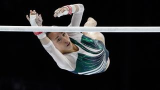 Kaylia Nemour of Algeria, in a white and green leotard, competes on the uneven bars ahead of the 2024 Paris Olympic Games.