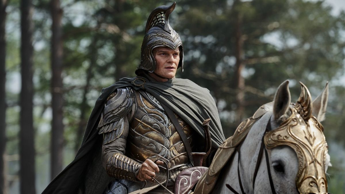 Robert Aramay as Elrond in armor and a helmet while riding a horse in Rings of Power Season 2.