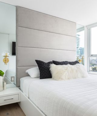 Apartment bedroom ideas illustrated with mirrored panels on either side of the bed, reflecting the window view