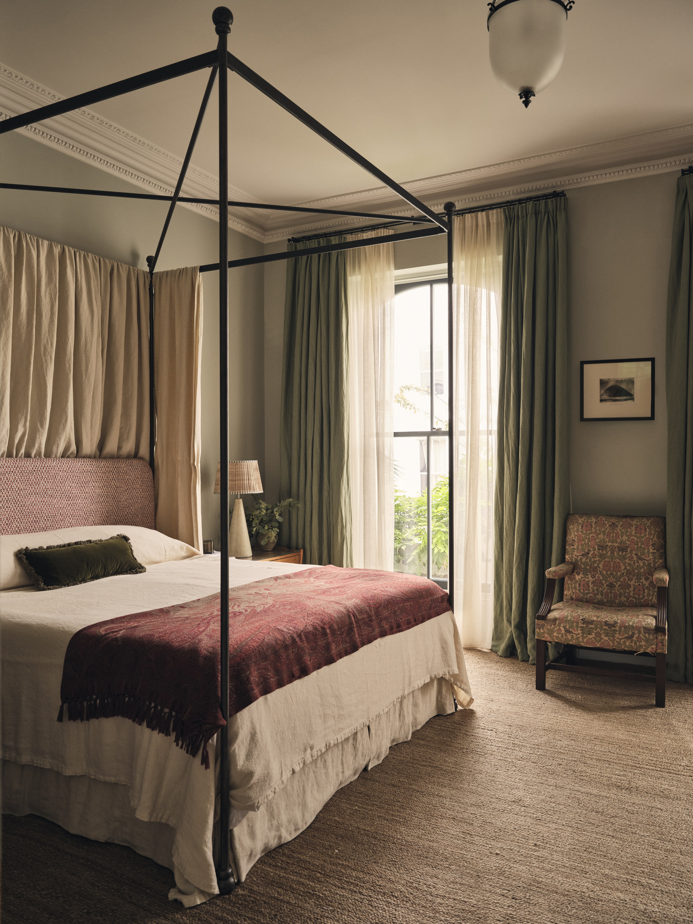 Bedroom featuring an iron four-post bed, sitting chair, and neutral texture wall-to-wall carpet