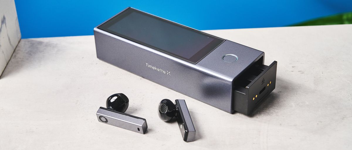 A black and gray Timekettle X1 AI Interpreter Hub translator with earbuds