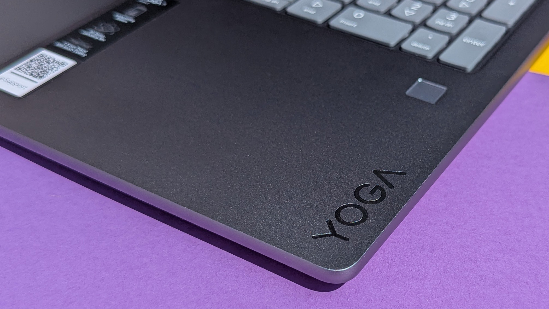 Lenovo Yoga 7i 16 (Gen 10) laptop with Yoga logo on purple and yellow card.