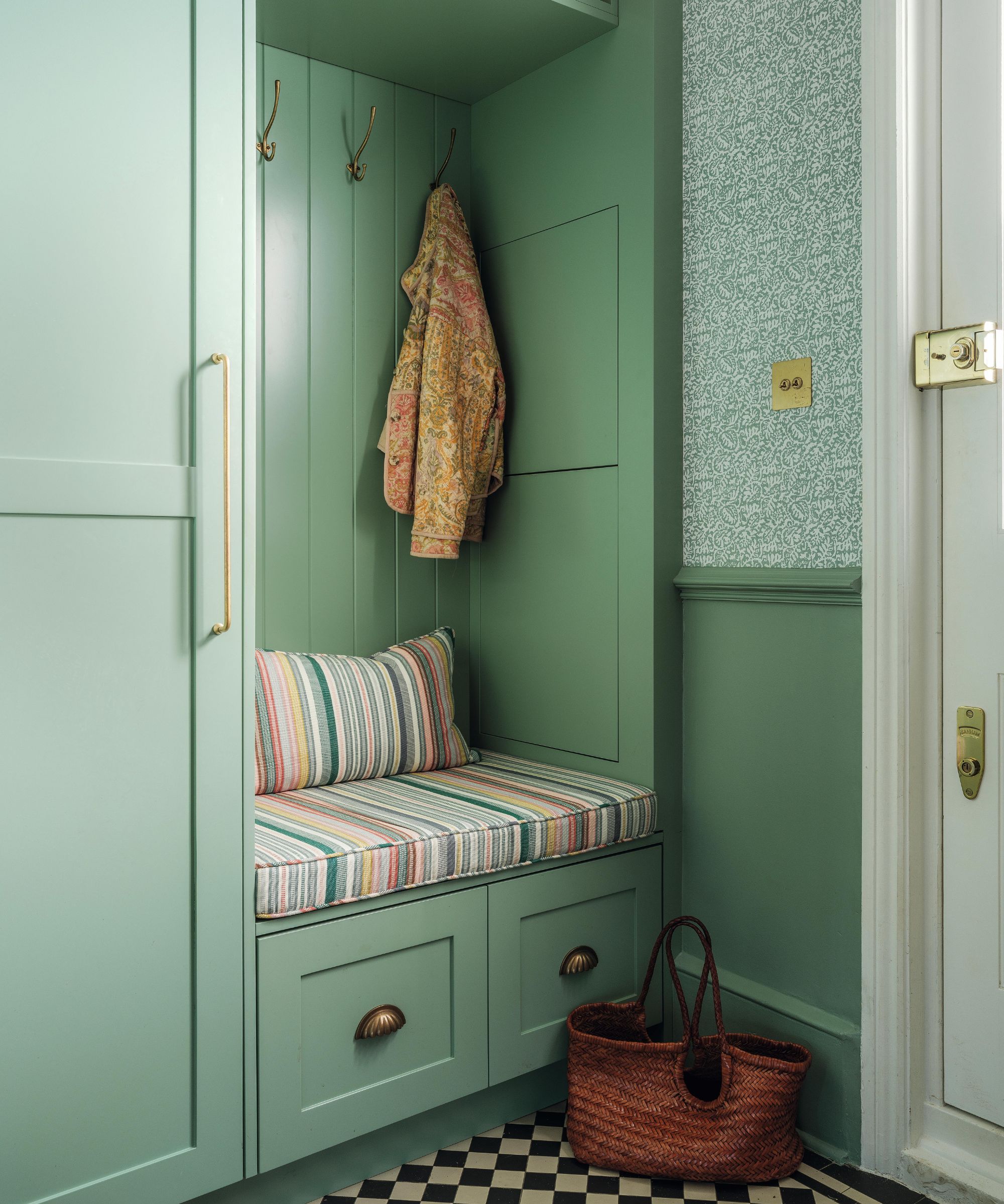 a green painted entryway with built in bench seta and storage