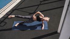A woman performing a side plank outside on a yoga mat as part of a core workout