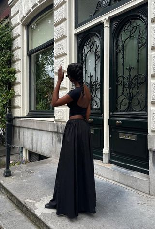 a black maxi skirt outfit showcasing a woman wearing black sunglasses with a black backless top and a black maxi skirt and black tabi ballet flats