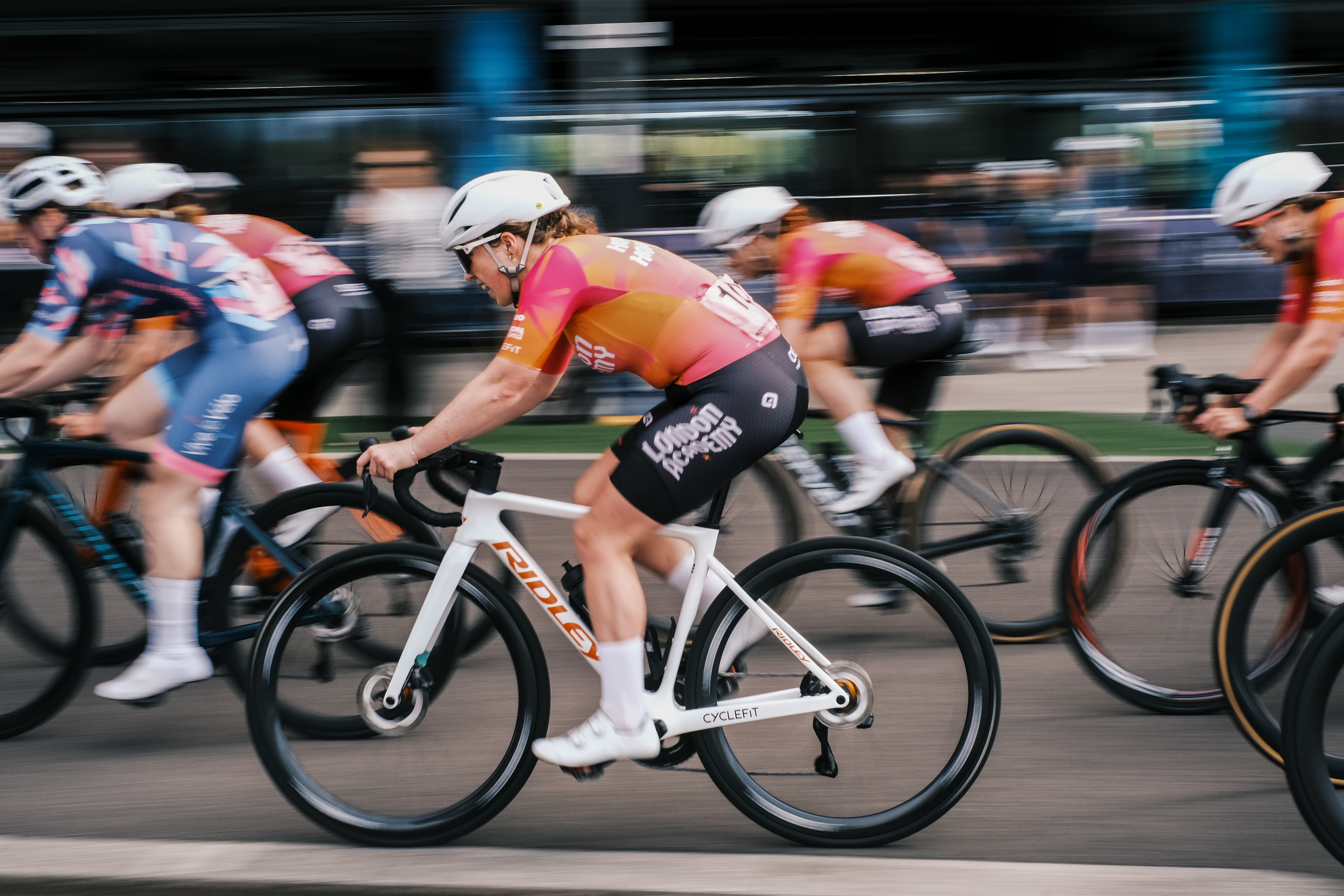A woman races a bike in a pink jersey