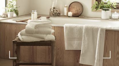 Rustic country bathroom with wood enclosed bath and fluffy white towels to support an article on how often should you wash your towels