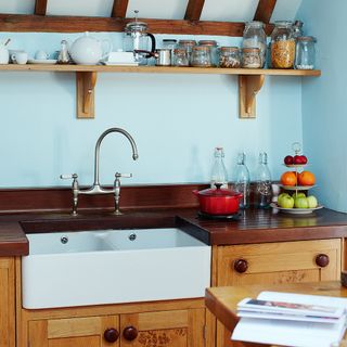 blue kitchen with wooden worktop and shelves
