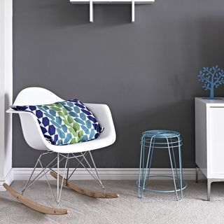 room with white chair grey wall metal stool and cushion