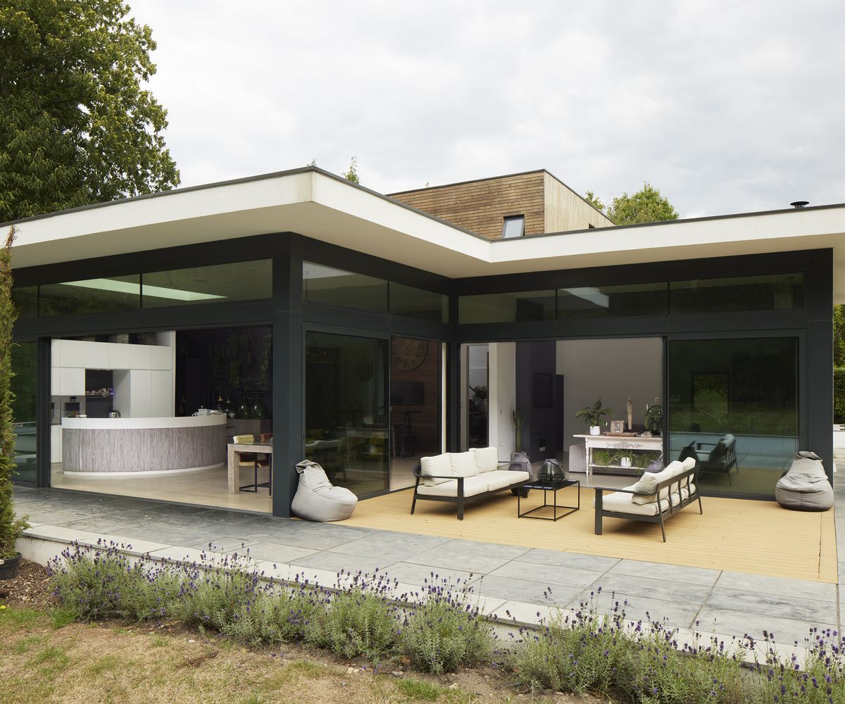 back view of a contemporary home self build with lawn and outdoor living area and large open glass sliding doors