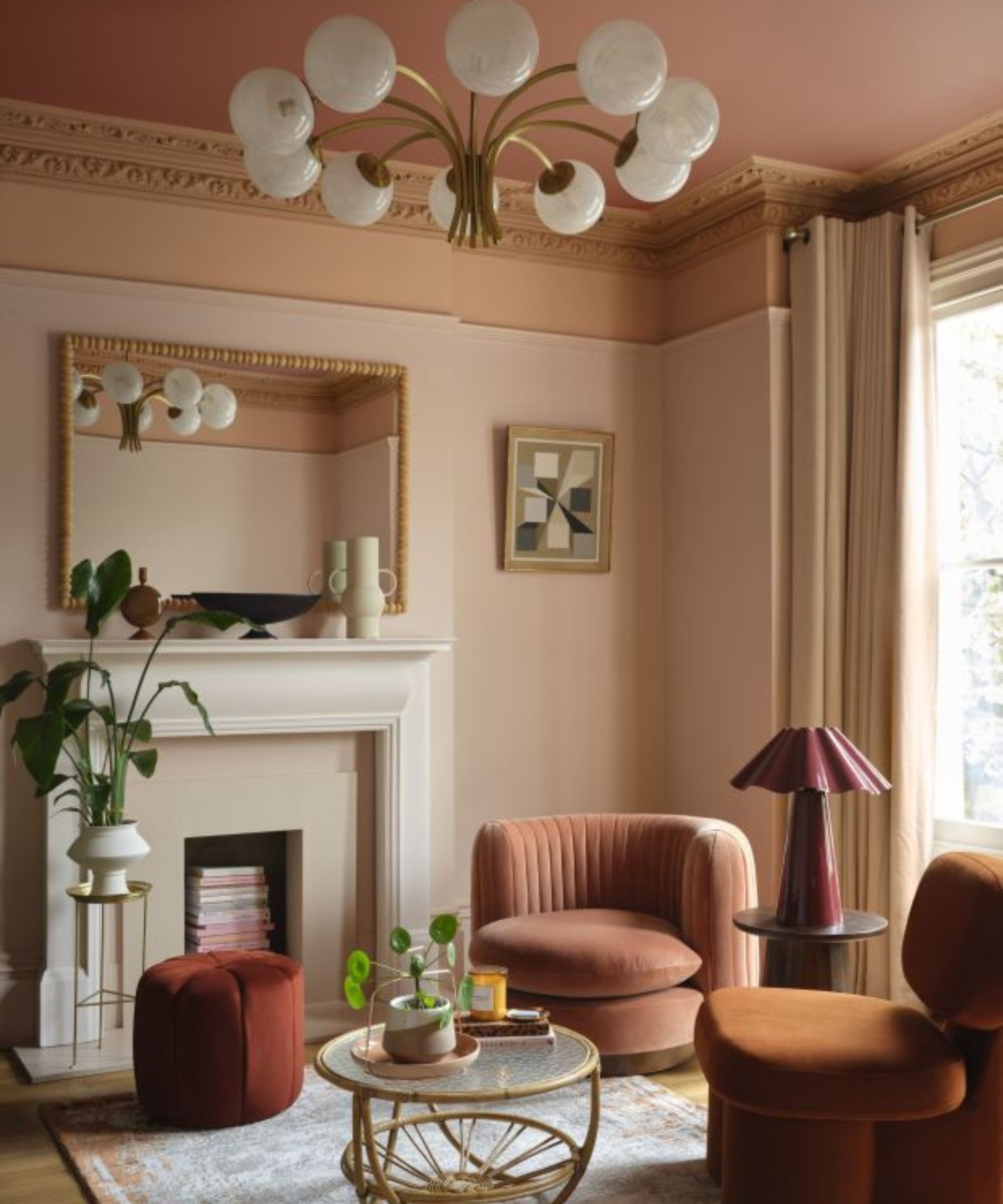 Terracotta orange living room with fireplace, pink ceiling, orange trim, blush velvet armchair and orange velvet armchair, rattan coffee table and plants