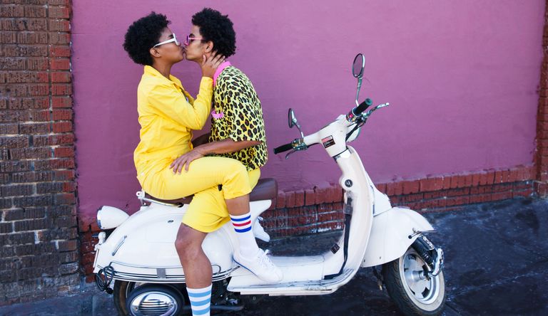 Thursday dating app - a young couple wearing yellow outfits sitting on a scooter kissing