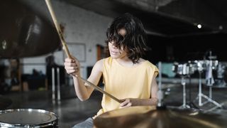 Boy in yellow t-shirt plays the drums