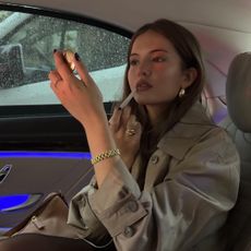 Image of a woman applying lip liner in the car.