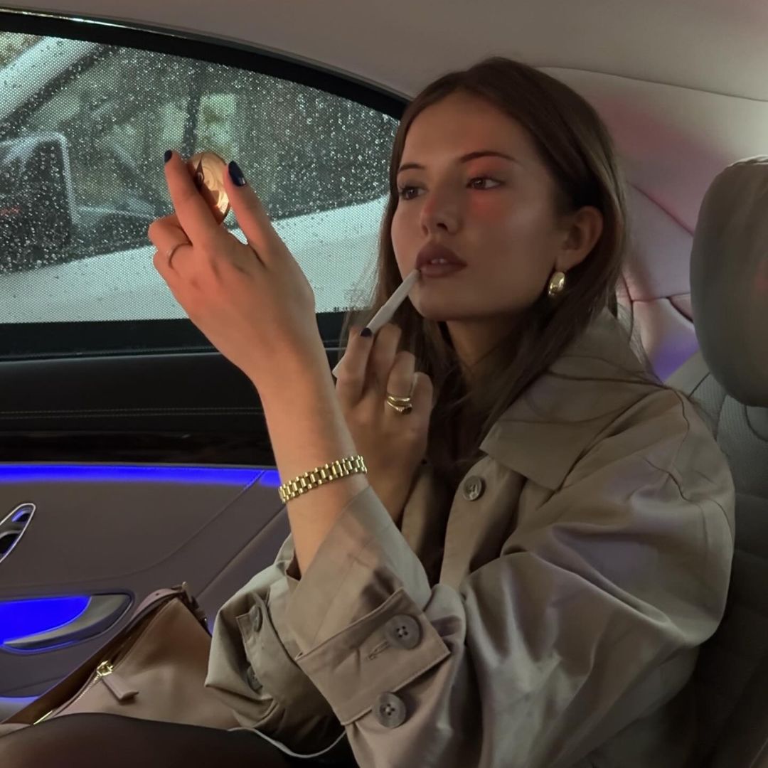 Image of a woman applying lip liner in the car.