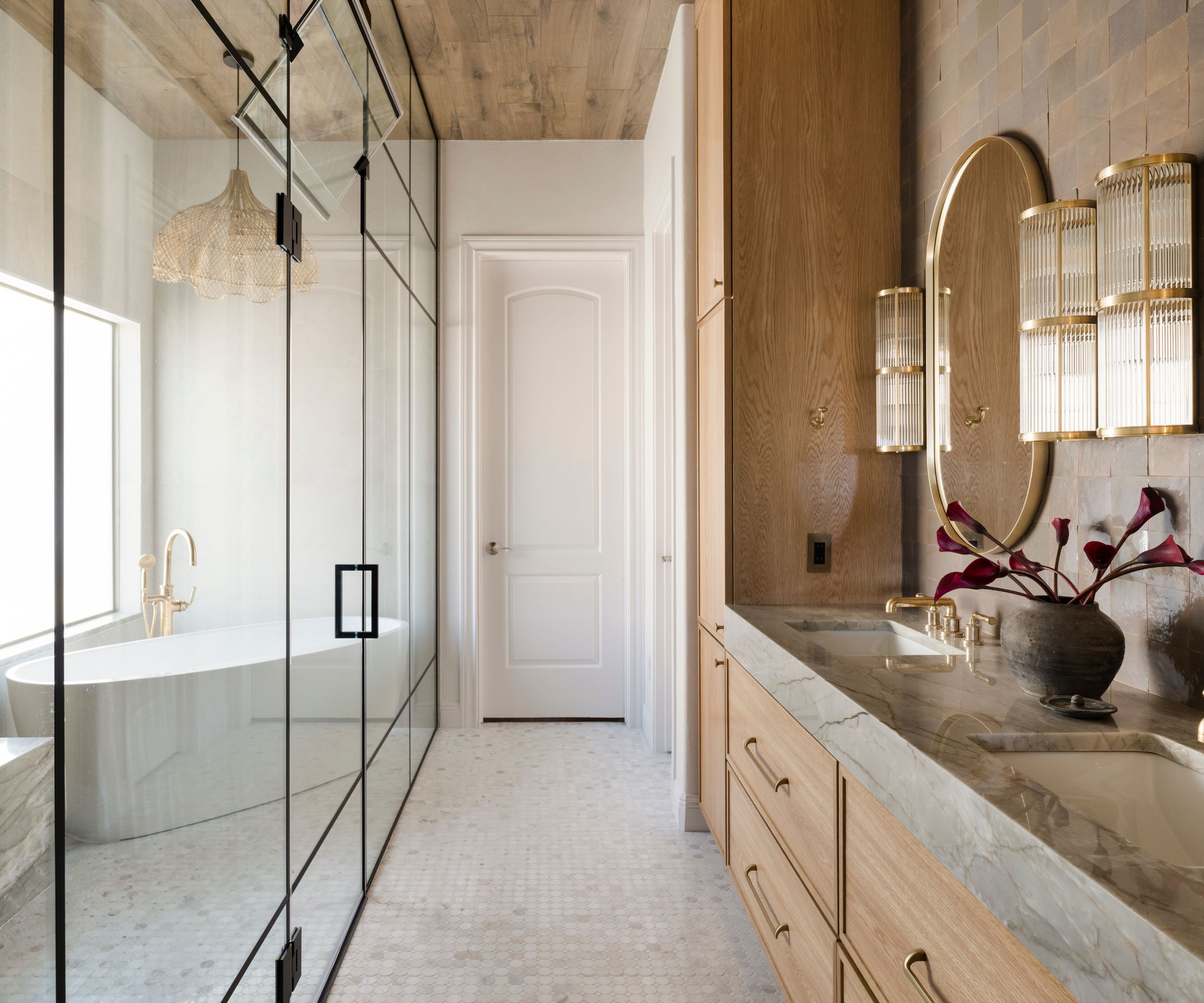 A wood and white bathroom with a broken layout, a glass divider separating the shower and bath from the vanity and storage