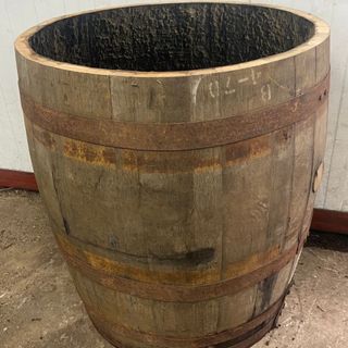 A wooden barrel repurposed as an oversized plant pot