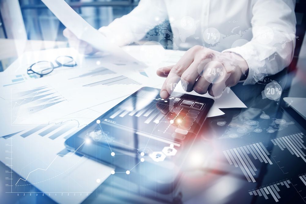 Image showing what is data processing with man working on a tablet with graphs at desk