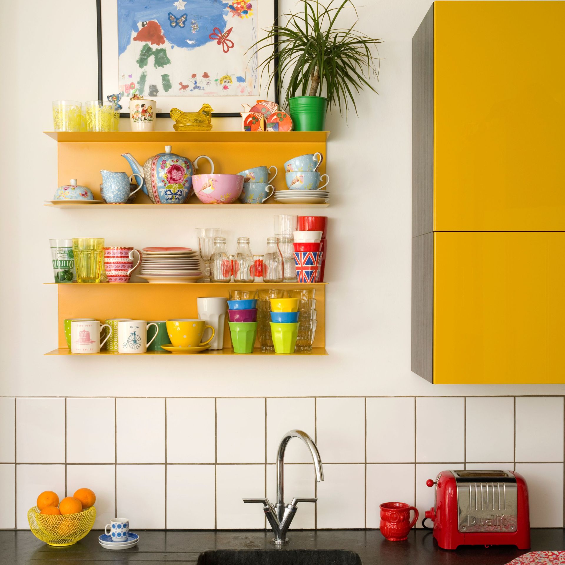 Closeup of white kitchen sink area. Grey marble worktop, yellow shelf and cabinet, tiled splashback