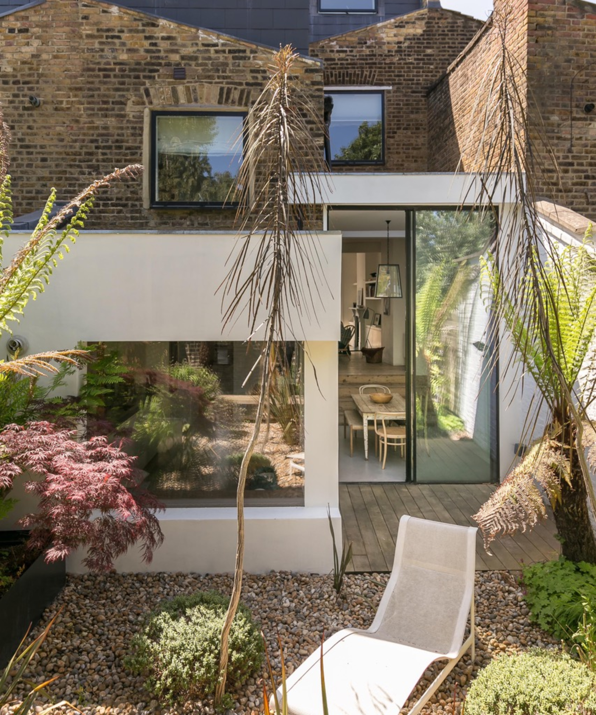 side and rear extension to victorian house finished in cream render with large glazed patio doors leading to gravel courtyard