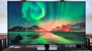 The Samsung QN90C OLED TV displaying a green landscape of the northern lights.