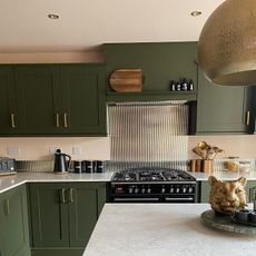 green kitchen with island and glass splashback