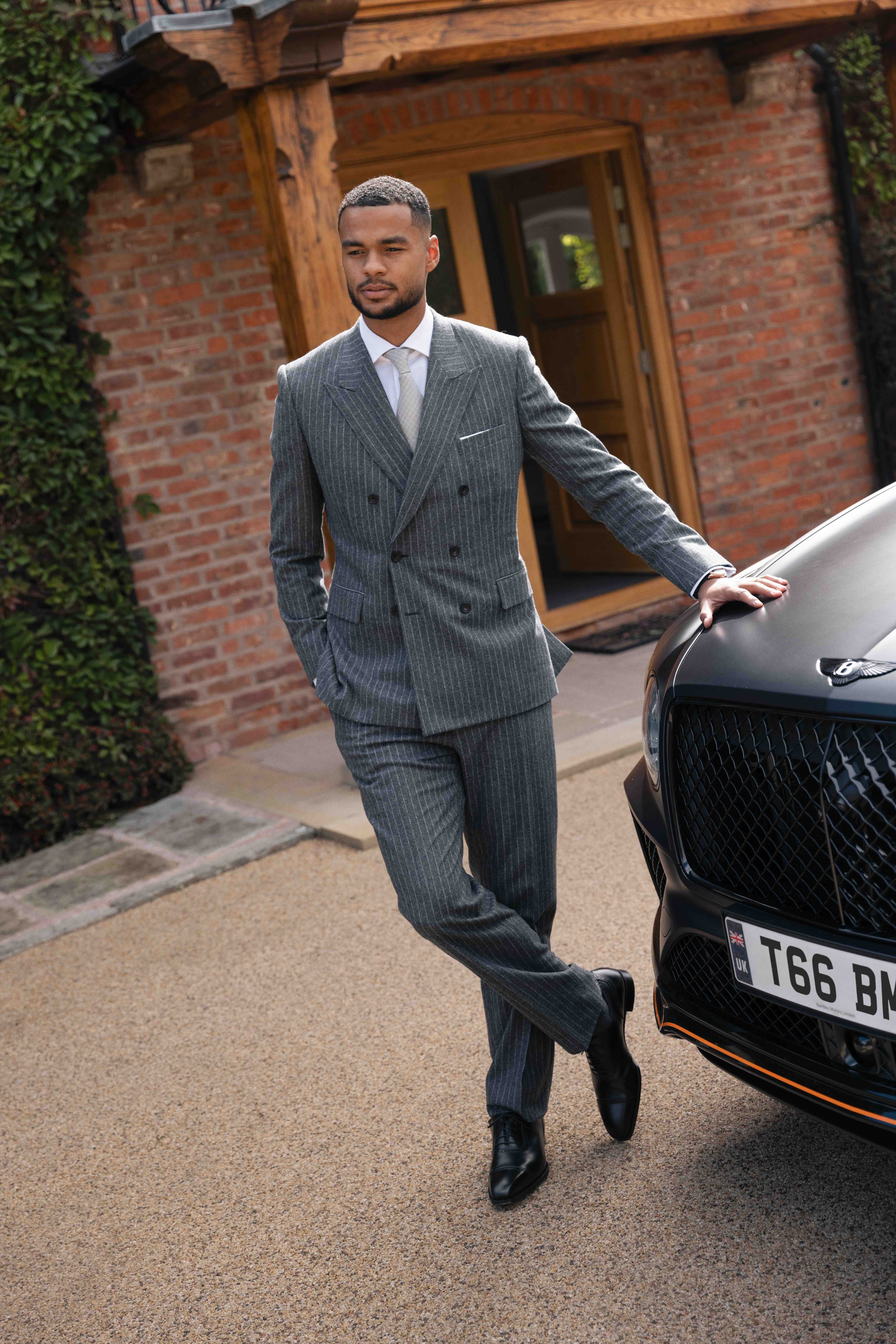 Cody Gakpo wears a fine grey pinstripe suit next to a Bentley Bentayga