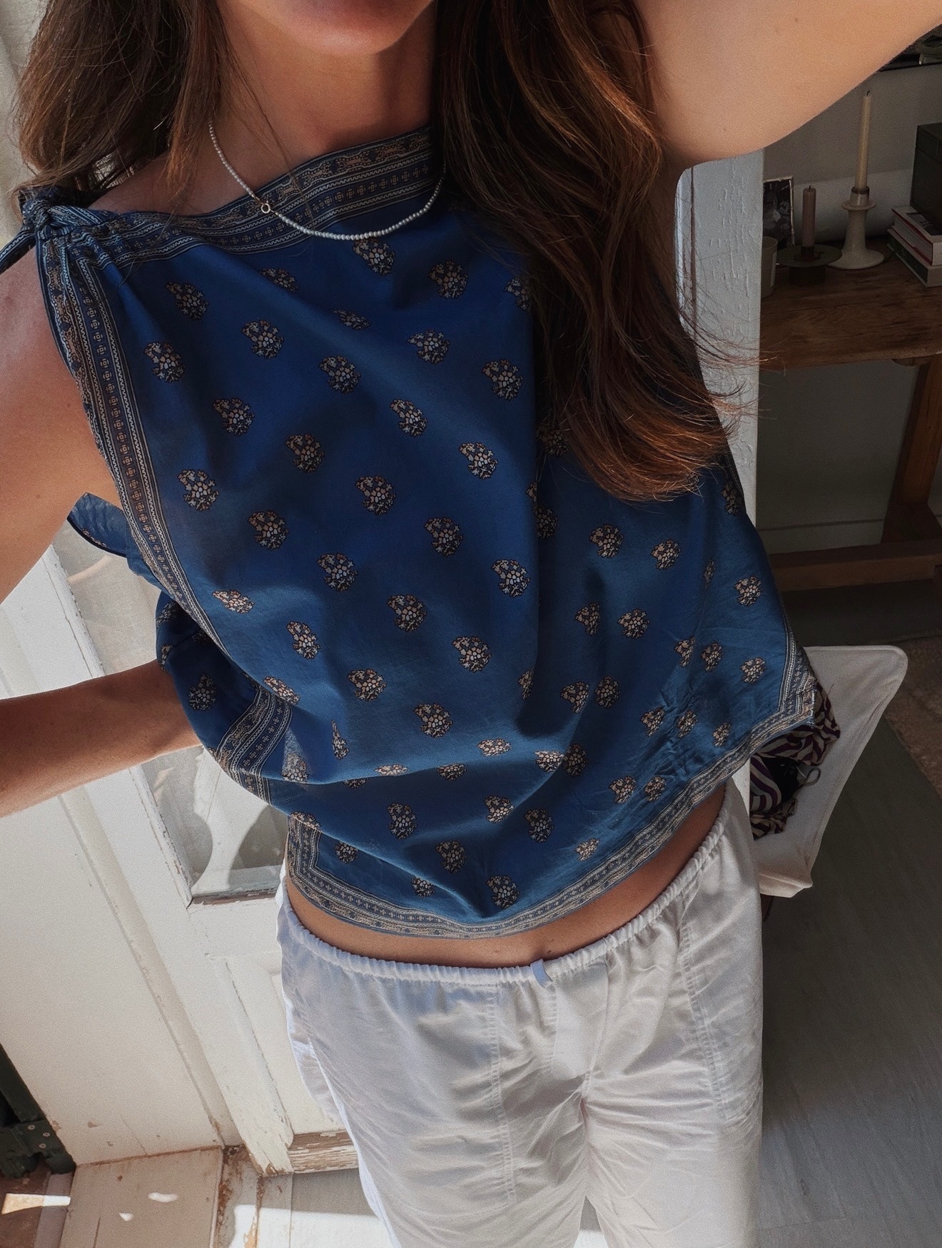 Woman in a scarf top and white pants