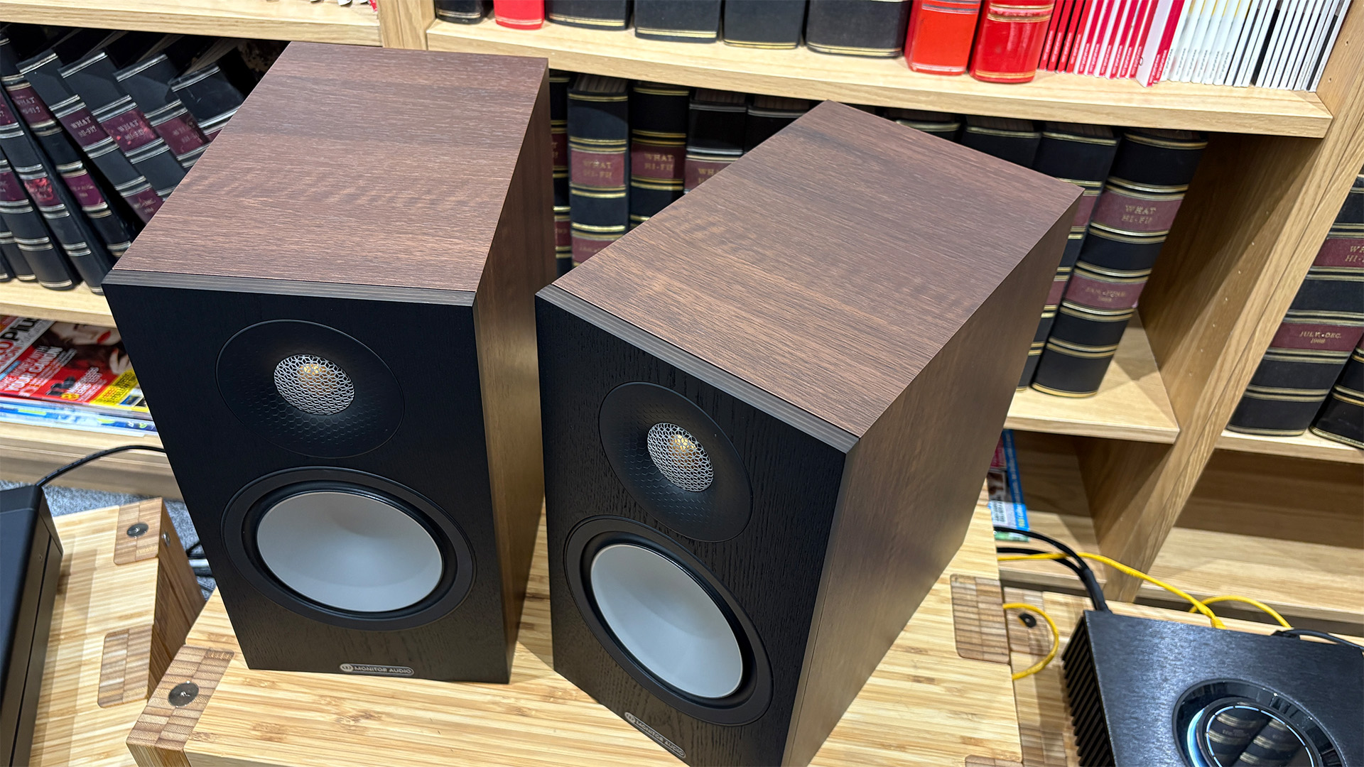 Monitor Audio Bronze 50 7G standmount speakers on wooden hi-fi rack in front of bookcase, angled top-down view