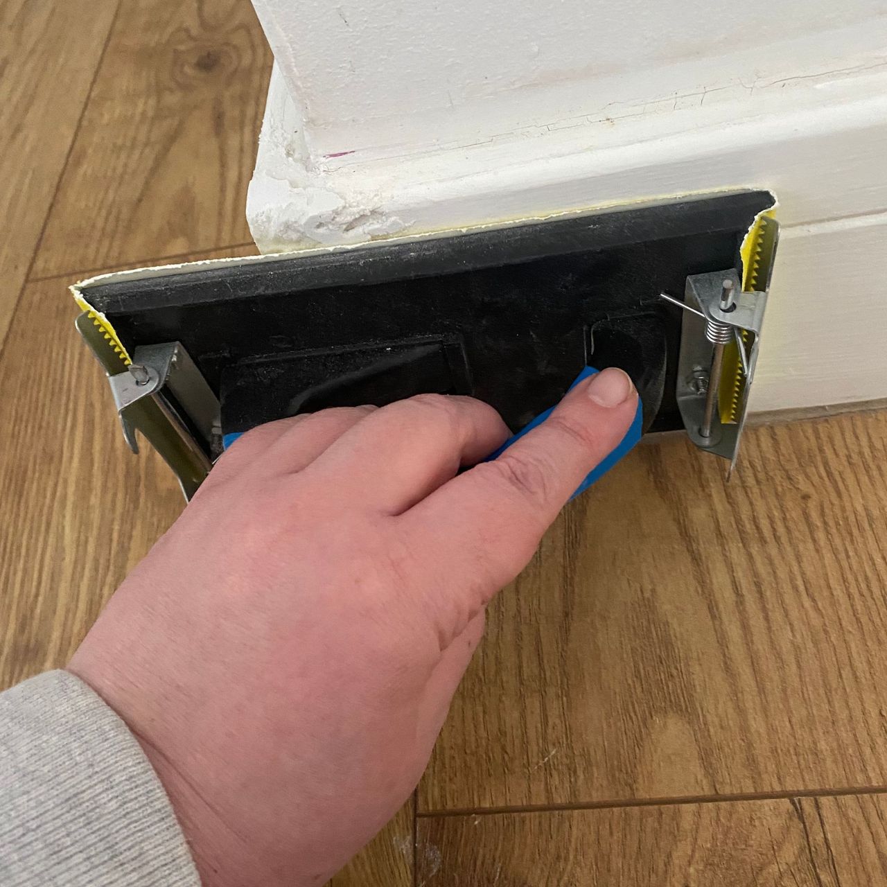 Using a hand sander tool to sand skirting boards