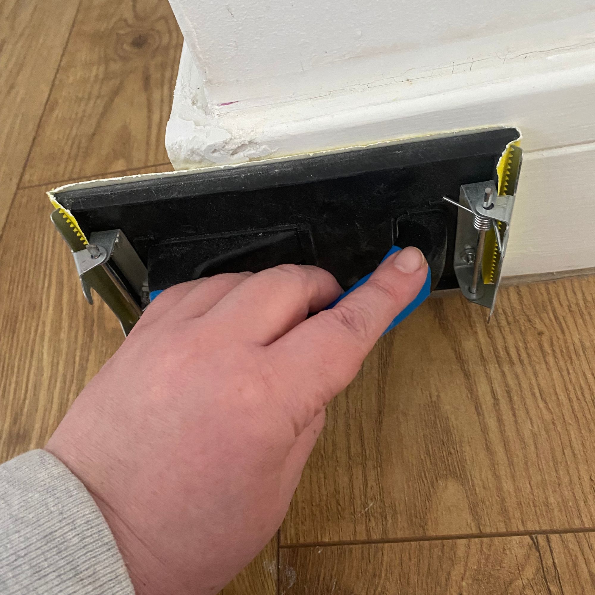 Using a hand sander tool to sand skirting boards