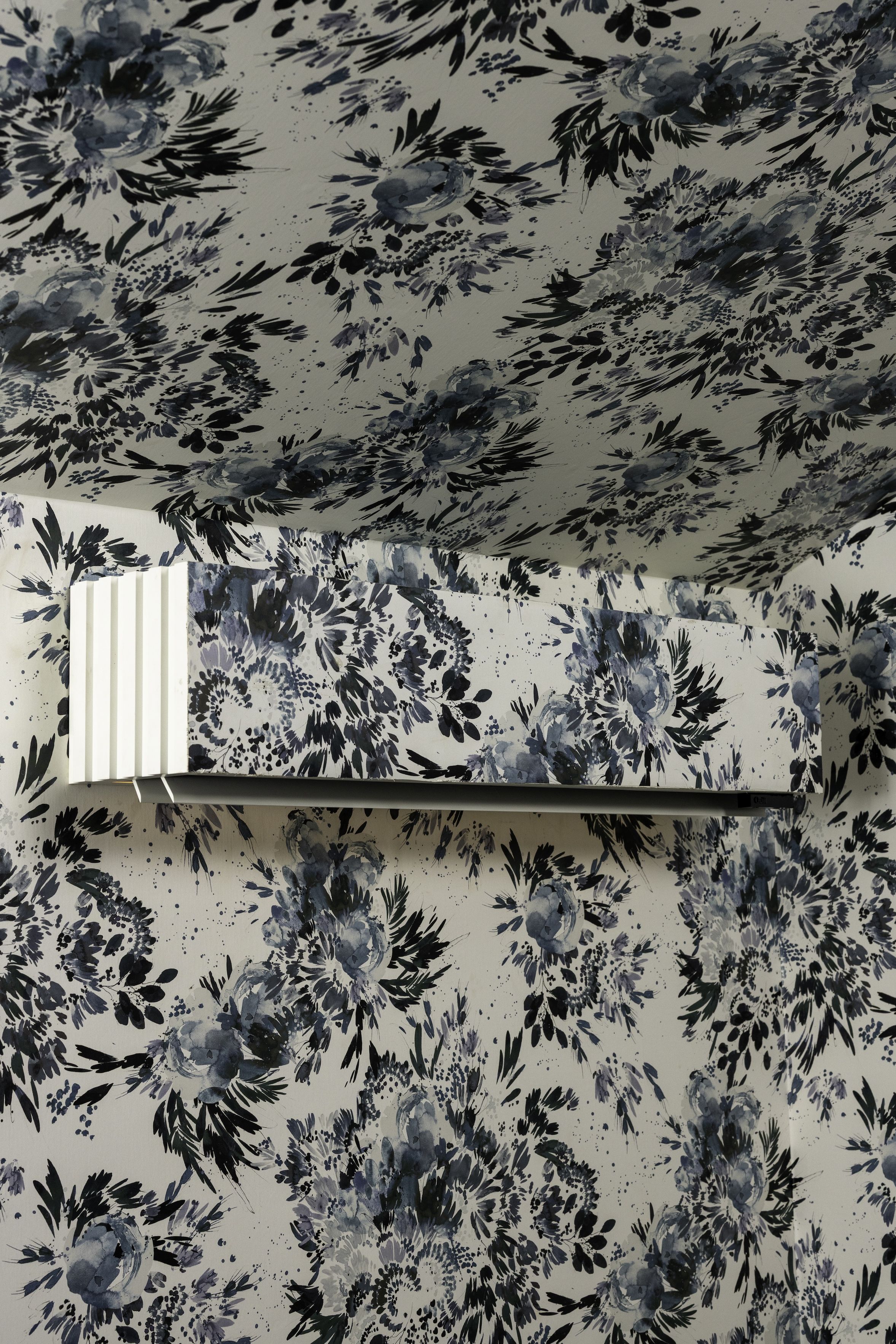 A ductless HVAC unit by Quilt, covered in the same floral wallpaper material as the wall. 