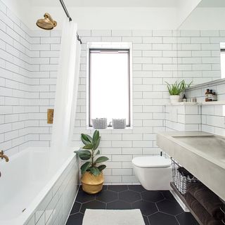 bathroom with white brick tiles wall black hexagon designed flooring window and bathtub