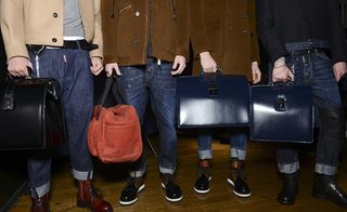Picture of four people's legs, wearing denim jeans and holding bags