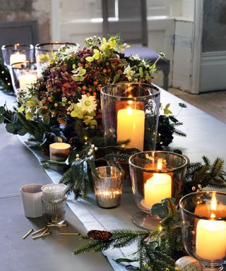 Thanksgiving centerpiece ideas with a pine foliage runner with floral centerpiece and candles