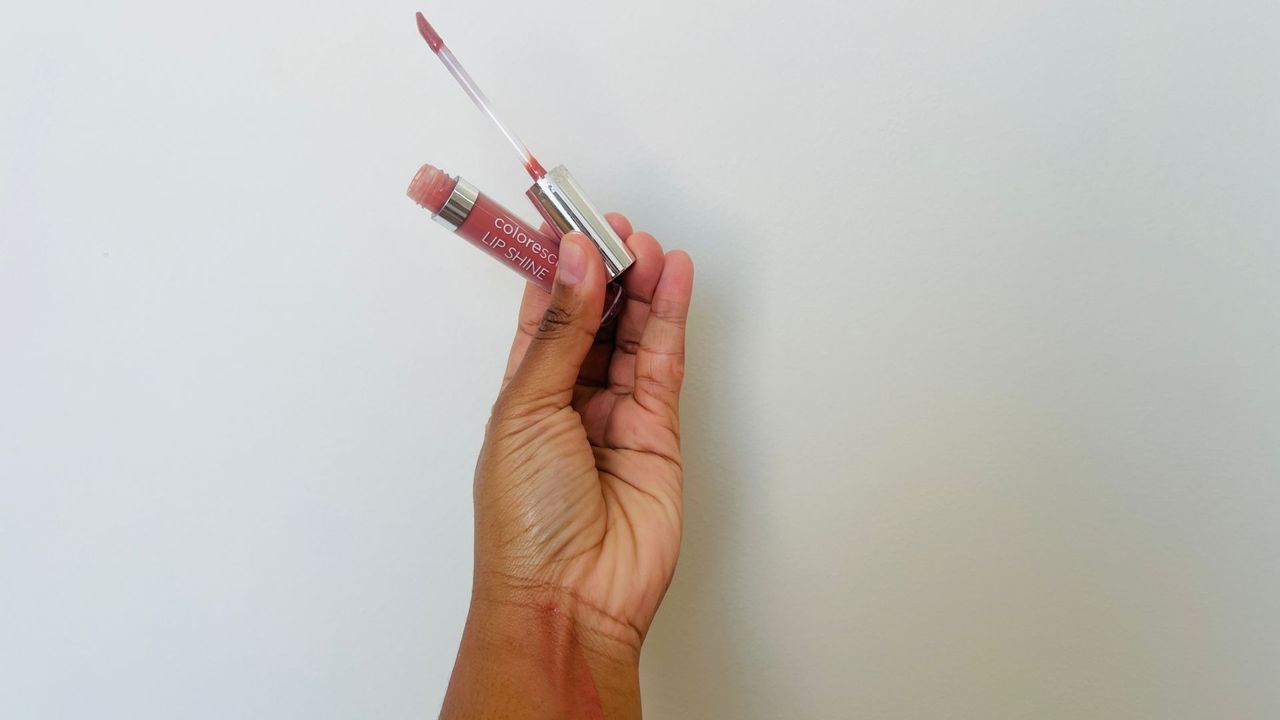 A person holding an opened pink Colorescience SPF lip balm.