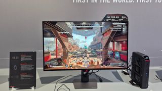 The Asus ROG Strix OLED XG32UCWMG monitor on a plain desk showing Apex Legends on screen