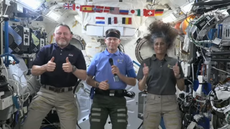 three astronauts give thumbs' up signs on the international space station