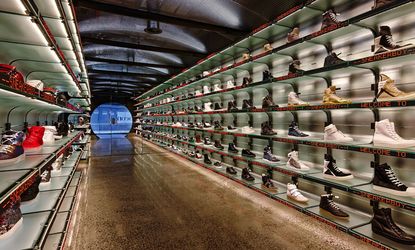 An aisle with six rows of sneakers on both sides. 