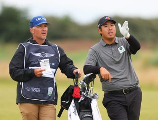 Byeong Hun An discusses a shot with his caddie