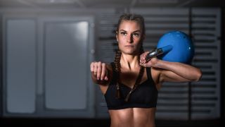 a photo of a woman with strong abs holding a kettlebell 