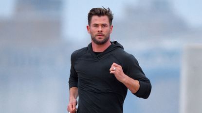 Chris Hemsworth runs on set in all black tracksuit