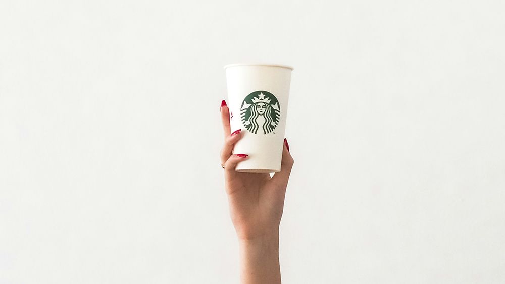 A hand holds a Starbucks coffee cup