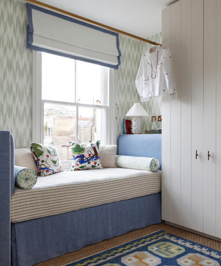 Small space with daybed that doubles as bed and cupboard and rug and wallpaper in pattern