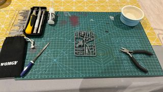 A cutting mat with various tools laid out on it, wit a model sprue in the center of it