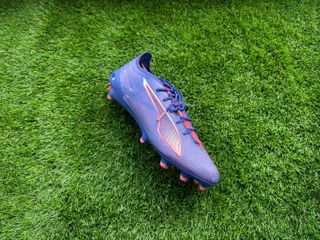 Puma Ultra 5 Ultimate soccer boots placed on a piece of astro turf for reviewing