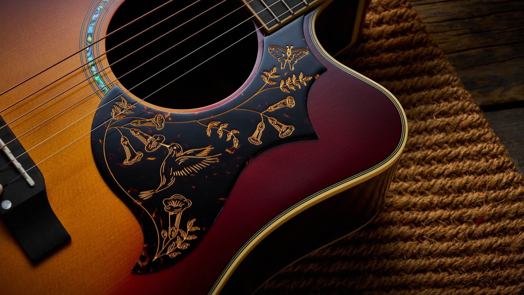 The Epiphone Inspired by Gibson Custom Hummingbird photographed in all its glory, in close-up and against a wheat-coloured rug.