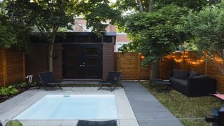 garden with swimming pool and soft string lighting draped over timber fencing, plus outdoor furniture