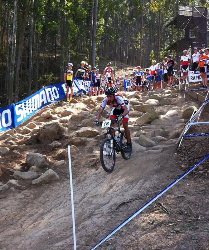 A crowd watches a rider from the top of a rock garden near the start/finish.