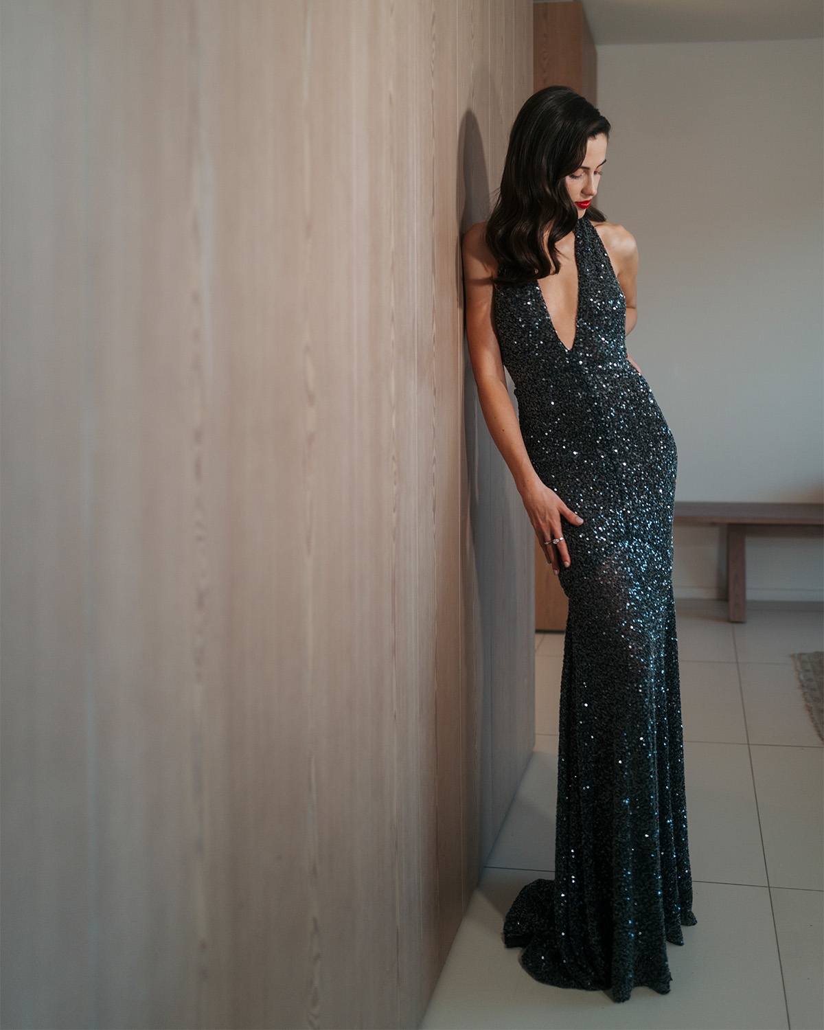 Lydia Peckham in her final look before hearing to the Nuremberg premiere. She is wearing a black sequin Patou gown with plunging halter neckline and a red lip.